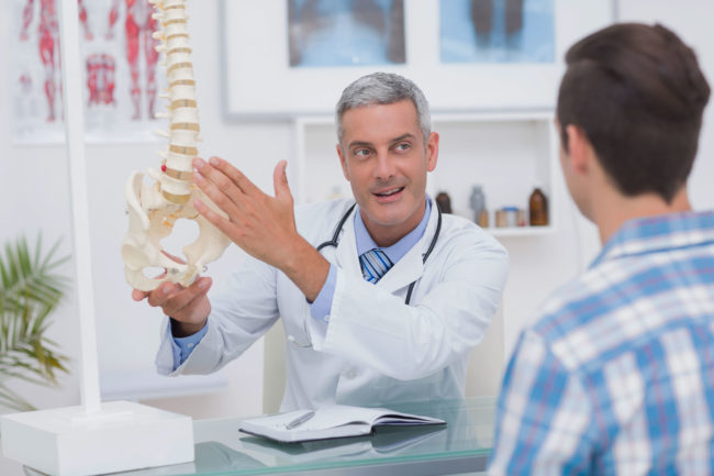 doctor showing his patient a spine model