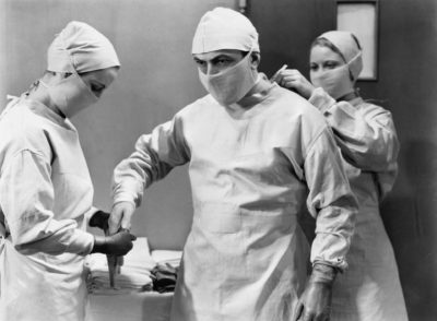 assistants preparing doctor for surgery