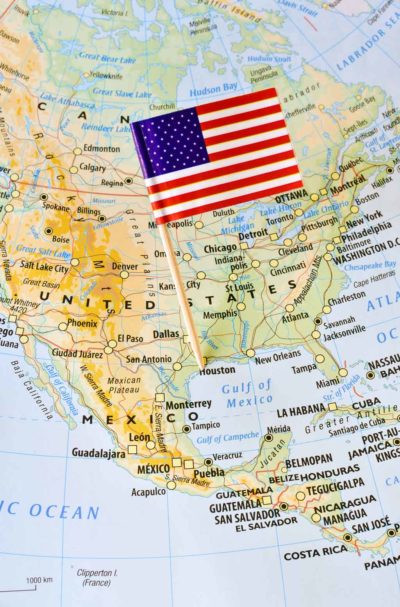 United States of America paper flag pin on a map showing countries and borders